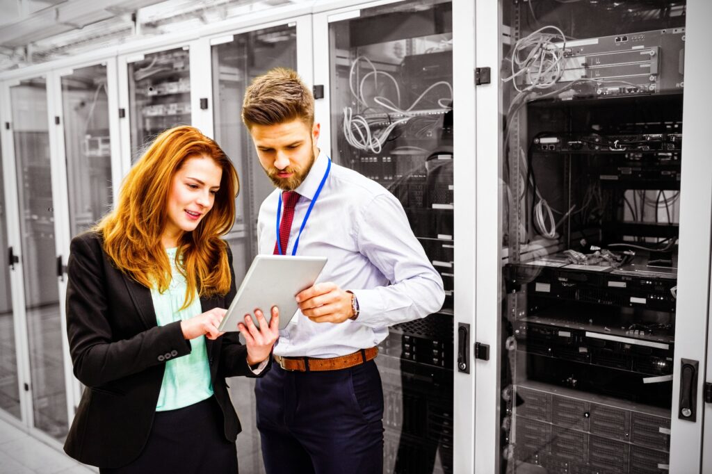 Technicians using digital tablet while analyzing server